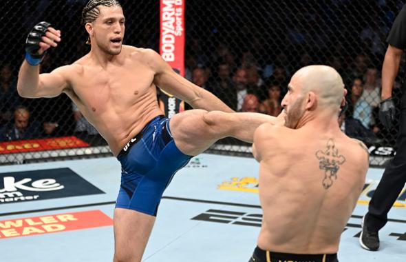 Brian Ortega kicks Alexander Volkanovski of Australia in their UFC featherweight championship fight during the UFC 266 event on September 25, 2021 in Las Vegas, Nevada. (Photo by Jeff Bottari/Zuffa LLC)